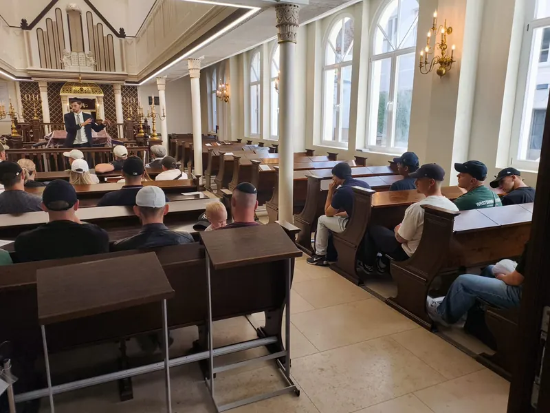 A group listening to an Ambassador in a synagogue