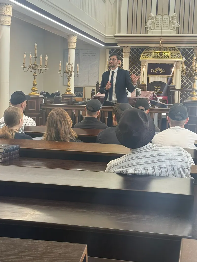 An Ambassador talking with visitors in a synagogue